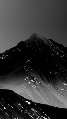 black and white photograph of a snowboarder in the air on top of a mountain