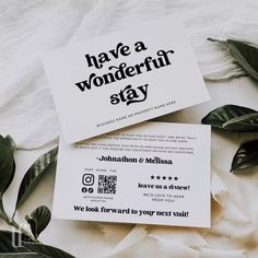 two business cards sitting on top of each other next to some leaves and white paper