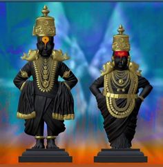 two black statues with gold decorations on their heads and arms, one standing in front of the other