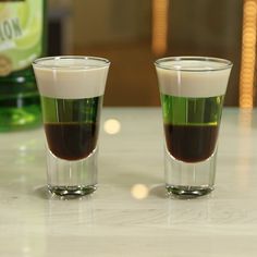 two shot glasses filled with liquid sitting on a table