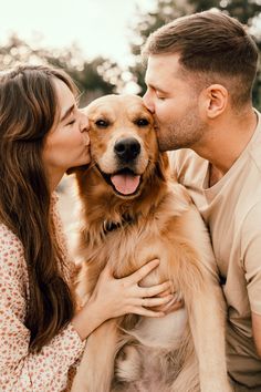 a man and woman kissing their dog on the cheek