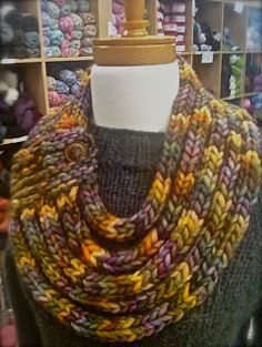 a mannequin wearing a multicolored knitted cowl in a store