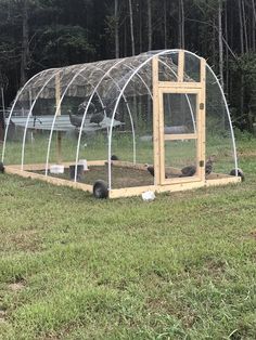 a chicken coop in the middle of a grassy field with chickens inside and on top of it