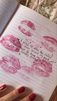 a notebook with lipstick drawn on it next to a woman's hand holding a pen