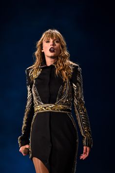 a woman in a black and gold dress on stage