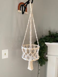 a white macrame hanging from a hook on the wall next to a fireplace