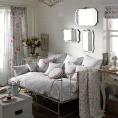 a living room filled with lots of furniture and flowers on the wall next to a window