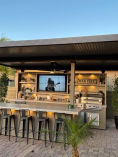 an outdoor bar with several stools and a television