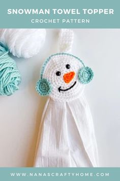 a crocheted snowman towel topper next to a ball of yarn on a table