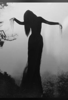 a woman standing in the fog with her arms outstretched