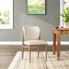 a chair sitting on top of a rug next to a wooden table with a potted plant