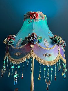 a fancy lamp with flowers and jewels on the bottom is lit by a blue background