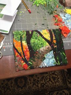 an art project is being done on a table with scissors and paintbrushes next to it