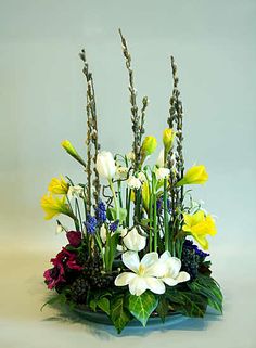 a vase filled with lots of different flowers on top of a blue tablecloth covered surface