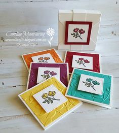 four cards with flowers on them sitting next to each other in front of a white wooden background