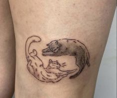 a woman's thigh with a cat and dog tattoo on it