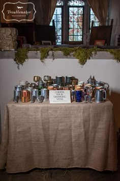 a table topped with lots of cups and saucers on top of a cloth covered table