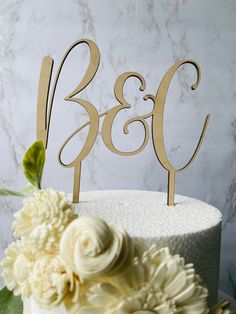 a white cake topped with a wooden monogrammed number