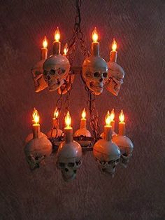 a chandelier with skulls hanging from it's sides and lit candles in the middle