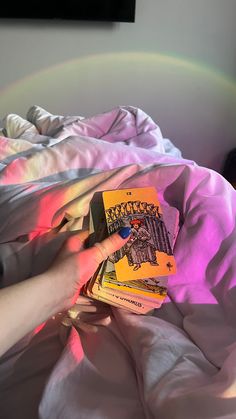 a person laying in bed reading a book with a rainbow light on the wall behind them