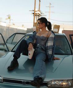 a woman sitting on the hood of a car