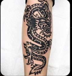 a black and white tattoo on the leg of a person with a dragon design on it