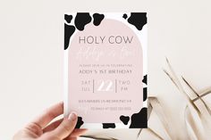 a person holding up a pink and black cow print birthday party card with the word, holly cow on it