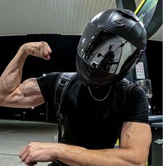 a man in a black shirt and helmet flexing his muscles