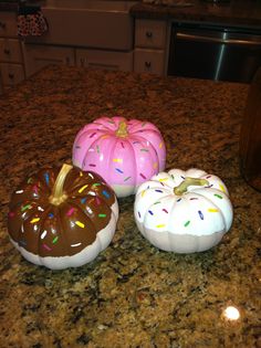 three donuts with sprinkles on them sitting on a kitchen counter top