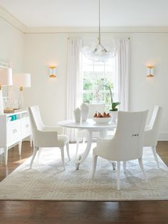 a white dining room table and chairs in front of a window with light coming through