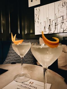 two martinis with orange peel garnish sit on a table