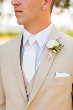 a man in a tan suit with a white rose boutonniere on his lapel