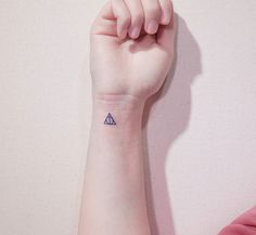 a woman's arm with a small triangle tattoo on her left wrist and the other hand