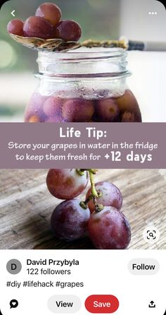 a jar filled with grapes sitting on top of a wooden table next to an iphone