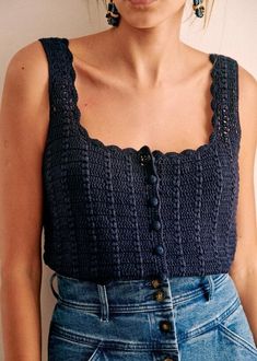 a close up of a person wearing jeans and a top with crochet on it