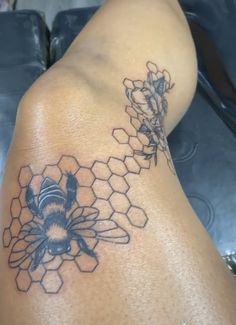 a tattoo on the back of a woman's leg with a bee and honeycomb