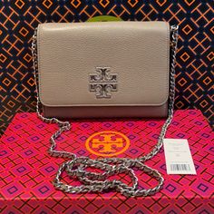 Nwt Auth Tory Burch Britten Chain Wallet Color Is French Gray Logo Is Hammered Silver Metal The Strap Has Leather Intertwined In The Metal Pebbled Leather Front Flap With Double Magnetic Snap Closure 1 Exterior Slip Pocket On Back 2 Interior Slip Pockets, 8 Card Slots, 1 Zip Pocket. Logo Lining Strap With (Approx.) 23" Drop Approximate Measurements 5.5" H X 7.5"L X 1.5" Silver Rectangular Wallet On Chain With Strap, Elegant Silver Leather Wallet On Chain, Silver Leather Wallet On Chain With Chain Strap, Rectangular Wallet On Chain With Silver-tone Hardware, Everyday Wallet On Chain With Palladium Hardware, Silver Rectangular Wallet On Chain For Everyday Use, Silver Wallet On Chain For Everyday Use, Tory Burch Britten, Brown Leather Crossbody Purse