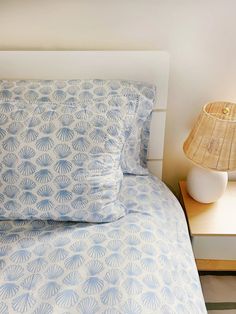 a bed with blue and white bedspread next to a lamp on a nightstand