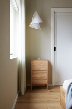 a bedroom with a bed, dresser and lamp hanging from it's side wall