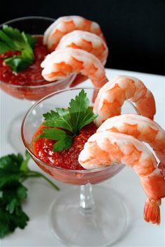 shrimp sticks are garnished with parsley and tomato sauce in small wine glasses