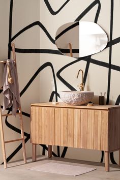 a bathroom with black and white wallpaper next to a wooden sink cabinet in front of a mirror