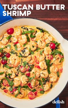 a pan filled with shrimp and spinach on top of a wooden table