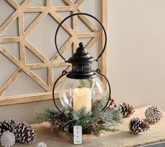 a candle is sitting on a table with pine cones and evergreens around it, along with other decorations