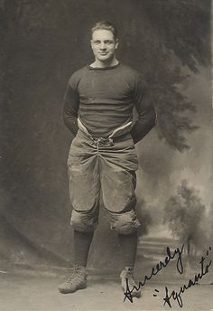 an old black and white photo of a man in football uniform holding a baseball bat