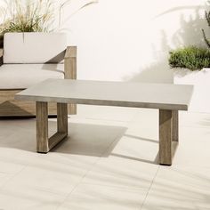 a concrete table sitting on top of a white tile floor next to a couch and chair