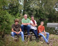 a group of people sitting on top of a bench next to a body of water