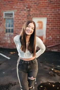 a young woman standing in front of a brick building with her hands on her hips