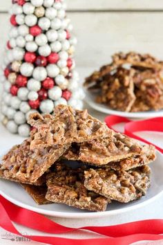 several pieces of granola on a white plate next to a christmas tree ornament