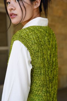 a woman with black hair wearing a green sweater