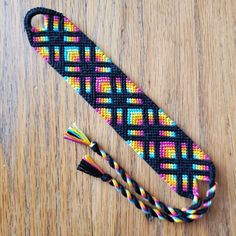 a multicolored tie sitting on top of a wooden table next to a pair of scissors